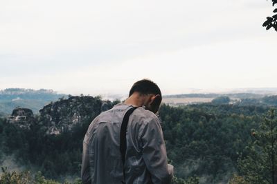 Rear view of man looking at landscape against sky