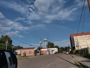 Road by buildings in city against sky