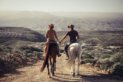 Couple riding horses on dirt road