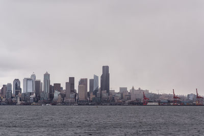 Sea by cityscape against sky