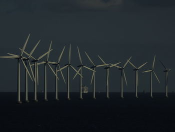 Windmills on beach against sky