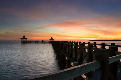 Pier over sea against sky during sunset