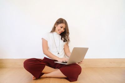 Portrait of young woman using phone while sitting on floor