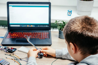 A boy plugging cables to sensor chips while learning arduino coding and robotics