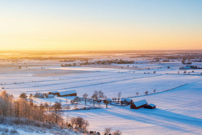 Scenic view of snow covered field against sky during sunset