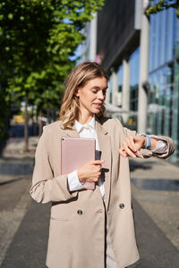 Portrait of young woman standing in city