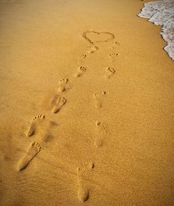 High angle view of couple footprints on sand at beach