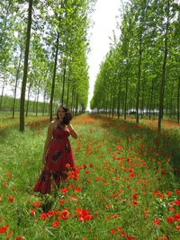 Rear view of woman standing on field against trees