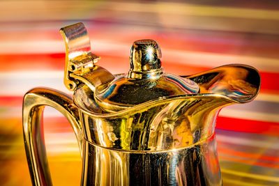 Shiny coffee pot in front of colorful background