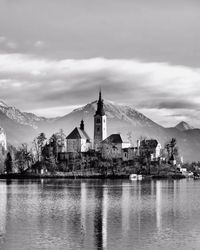 Church and houses amidst lake bled against cloudy sky