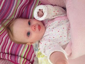 Portrait of baby girl relaxing on bed at home