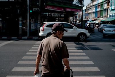 Rear view of man walking on road in city