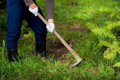 Low section of man cleaning grass with shovel in lawn