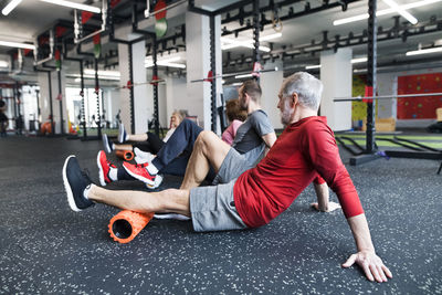 Group of fit seniors in gym using foam rollers
