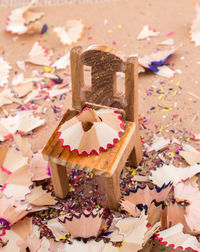 High angle view of pencil shavings with toy chair on wooden table