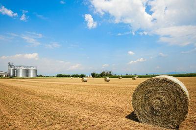 Hay bales on field against sky