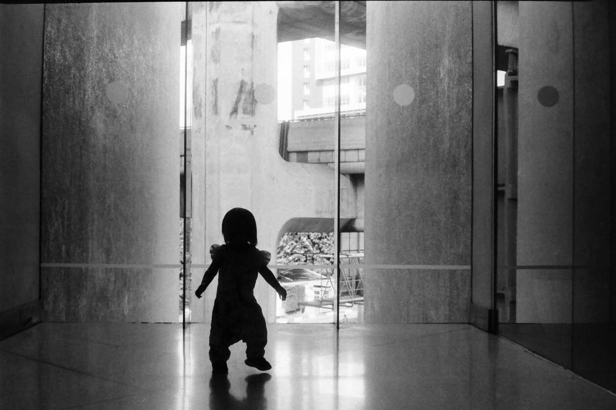 REAR VIEW OF A BOY STANDING AGAINST DOOR