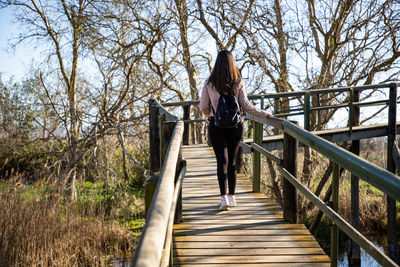 Rear view of man walking on footbridge