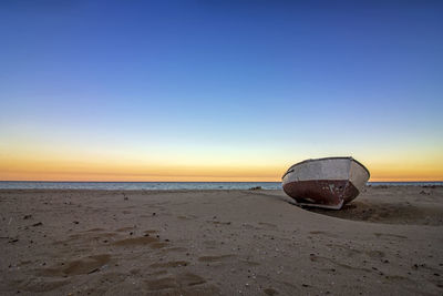 Boat on beach against sky during sunset