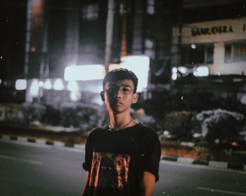 Portrait of young man standing in city at night