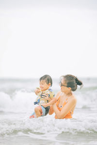 Portrait of happy family in sea against clear sky