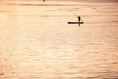 Silhouette man in boat on sea against sky