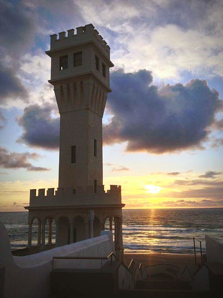 sunset, sea, sky, architecture, built structure, horizon over water, cloud - sky, water, building exterior, orange color, beach, scenics, cloud, beauty in nature, cloudy, shore, nature, sun, tranquility, tranquil scene