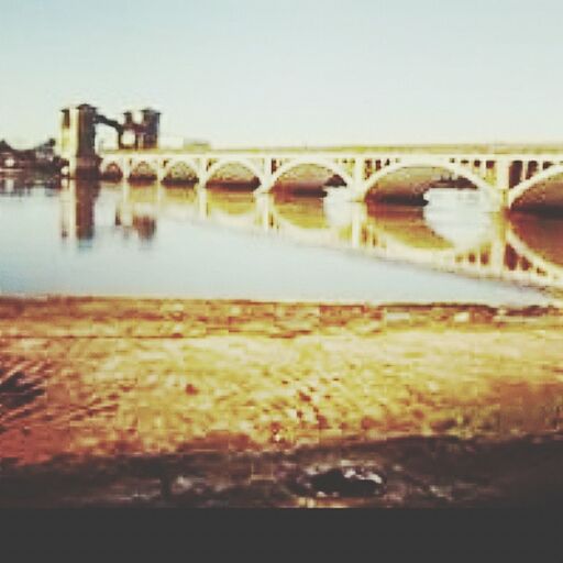 clear sky, water, bridge - man made structure, transportation, built structure, copy space, architecture, river, connection, sea, beach, bridge, no people, selective focus, outdoors, sky, reflection, waterfront, nature, focus on foreground