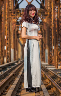 Portrait of young woman standing on railroad tracks