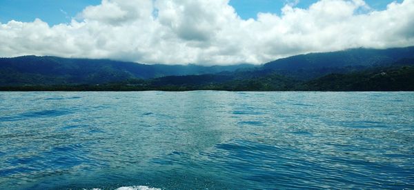 Scenic view of lake and mountains against cloudy sky