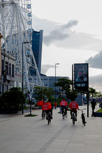 People in amusement park against sky in city