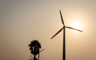 Low angle view of wind turbine against sky during sunset