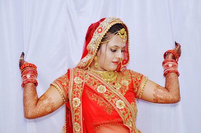 Bride looking away while standing against backdrop