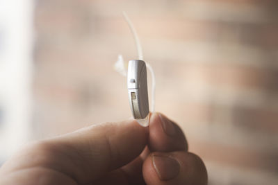 Close-up of hand holding hearing aid indoors
