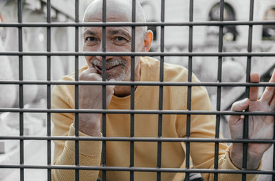 Capturing a moment of contemplation, the elderly man appears thoughtful he looks through metal bars
