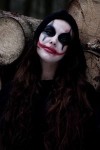 Portrait of woman in zombie make-up against logs