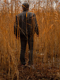 Rear view of man standing on field in forest