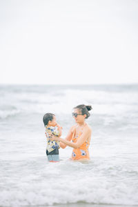 Smiling mother with son enjoying on sea water