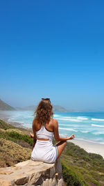 Rear view of woman looking at sea against clear sky