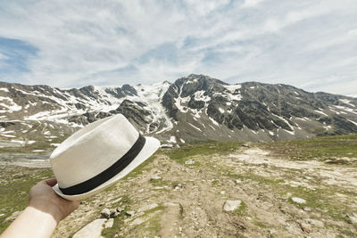 Midsection of person holding snowcapped mountain against sky