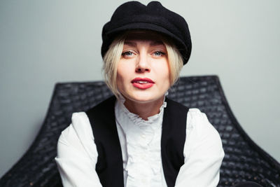 Portrait of young woman wearing cap against gray background