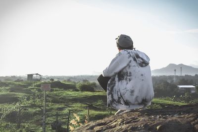 Rear view of man looking at field against clear sky