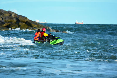 People in boat on sea against sky