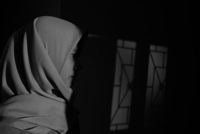 Close-up of woman wearing hijab standing in darkroom