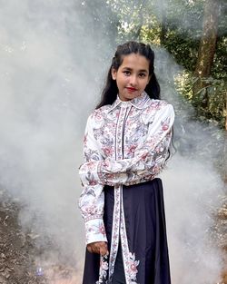 Portrait of young woman standing against smoke 