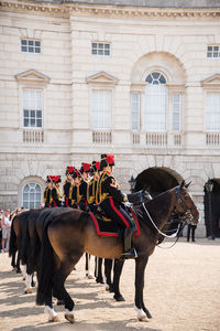 Soldiers riding horses by historic building