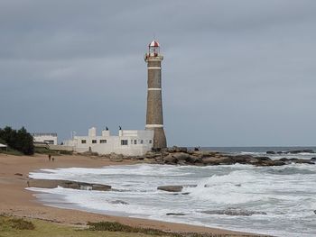 Lighthouse by sea against sky