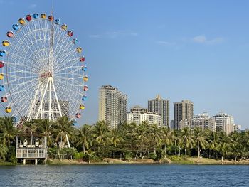 Ferris wheel by buildings against sky in city