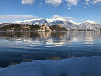 Scenic view of lake by snowcapped mountains against sky