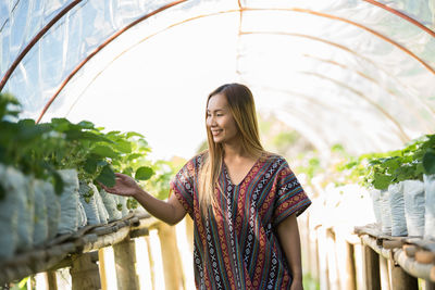 Smiling young woman working at greenhouse